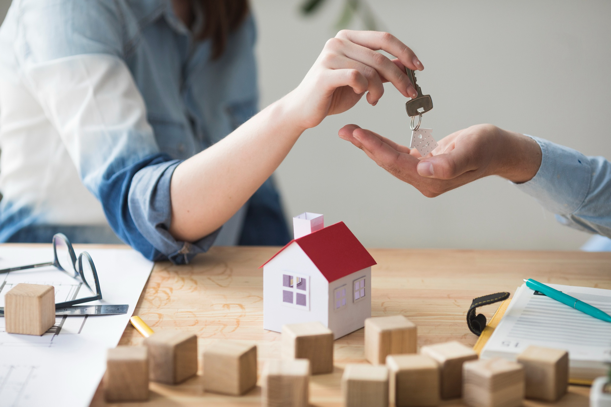 close up woman s hand giving house key man wooden table - Private Mortgage Lenders - Canada's Biggest Resource