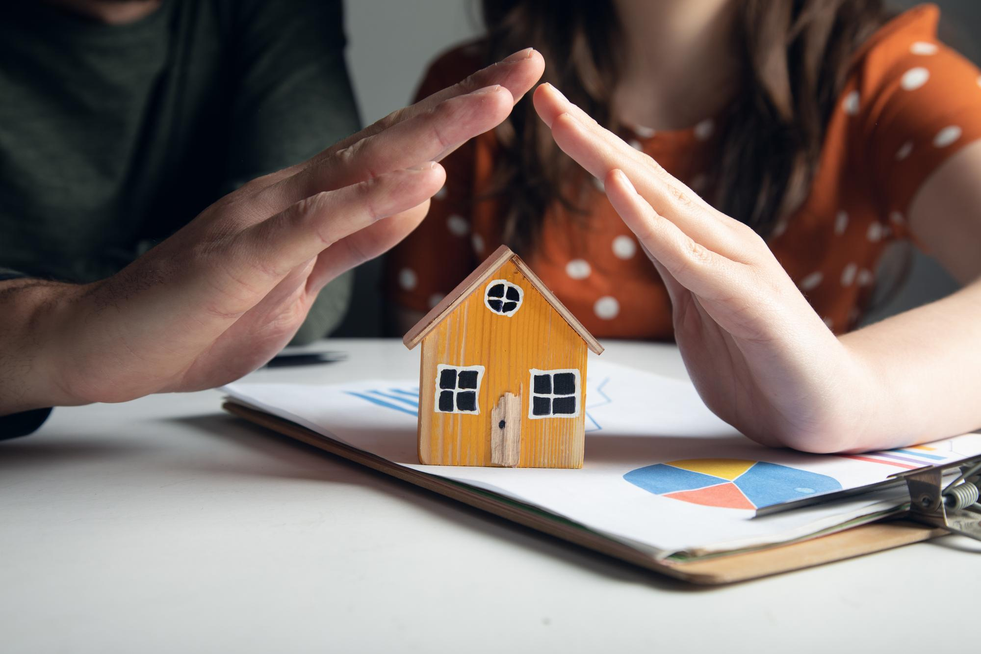 hands-family-couple-holding-model-house.jpg middle aged man shaking hands with a financial advisor during a consultation about second mortgage with bad credit at home