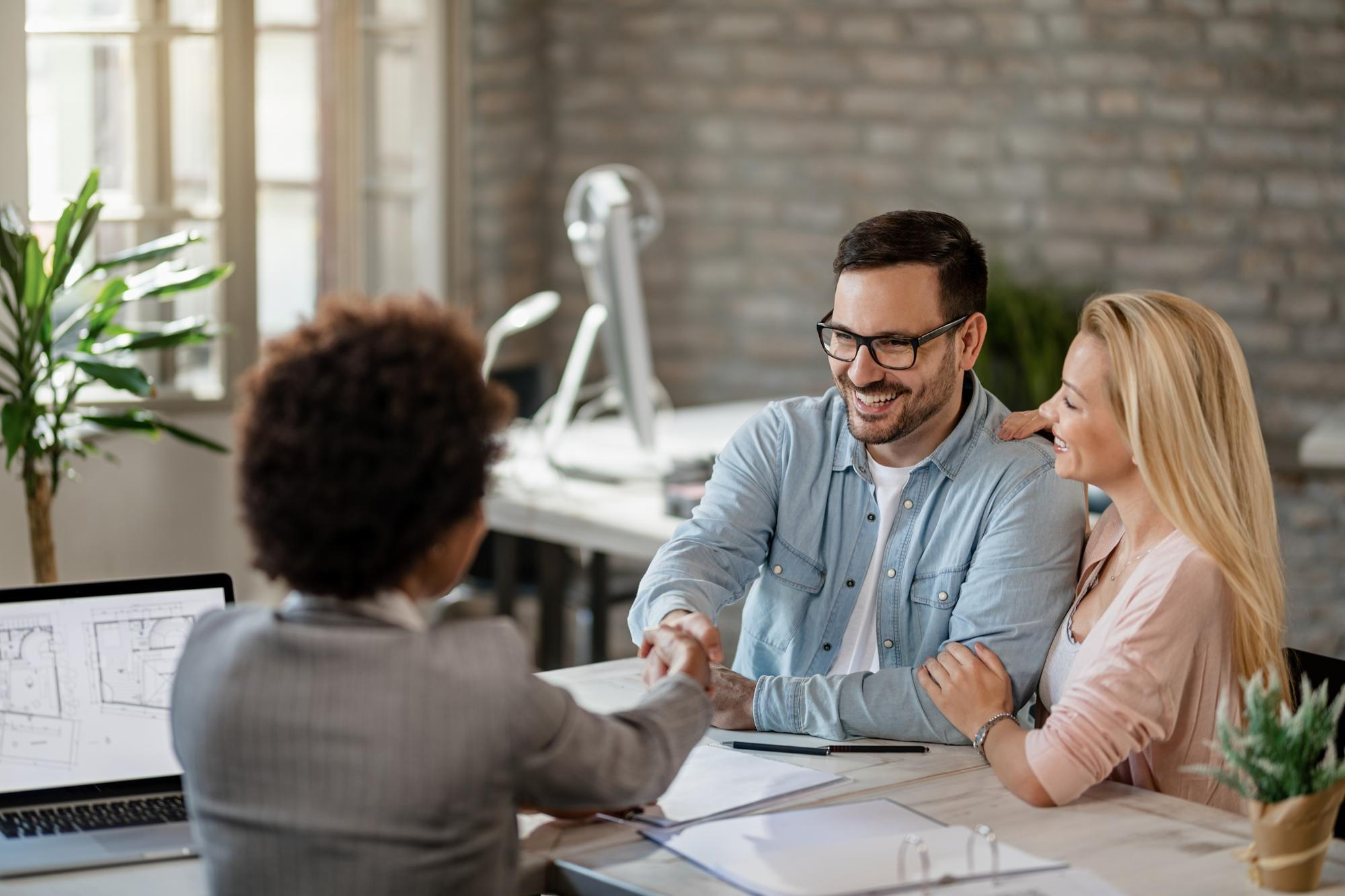 happy couple handshaking with financial advisor meeting office focus is man - How do I get an approval?