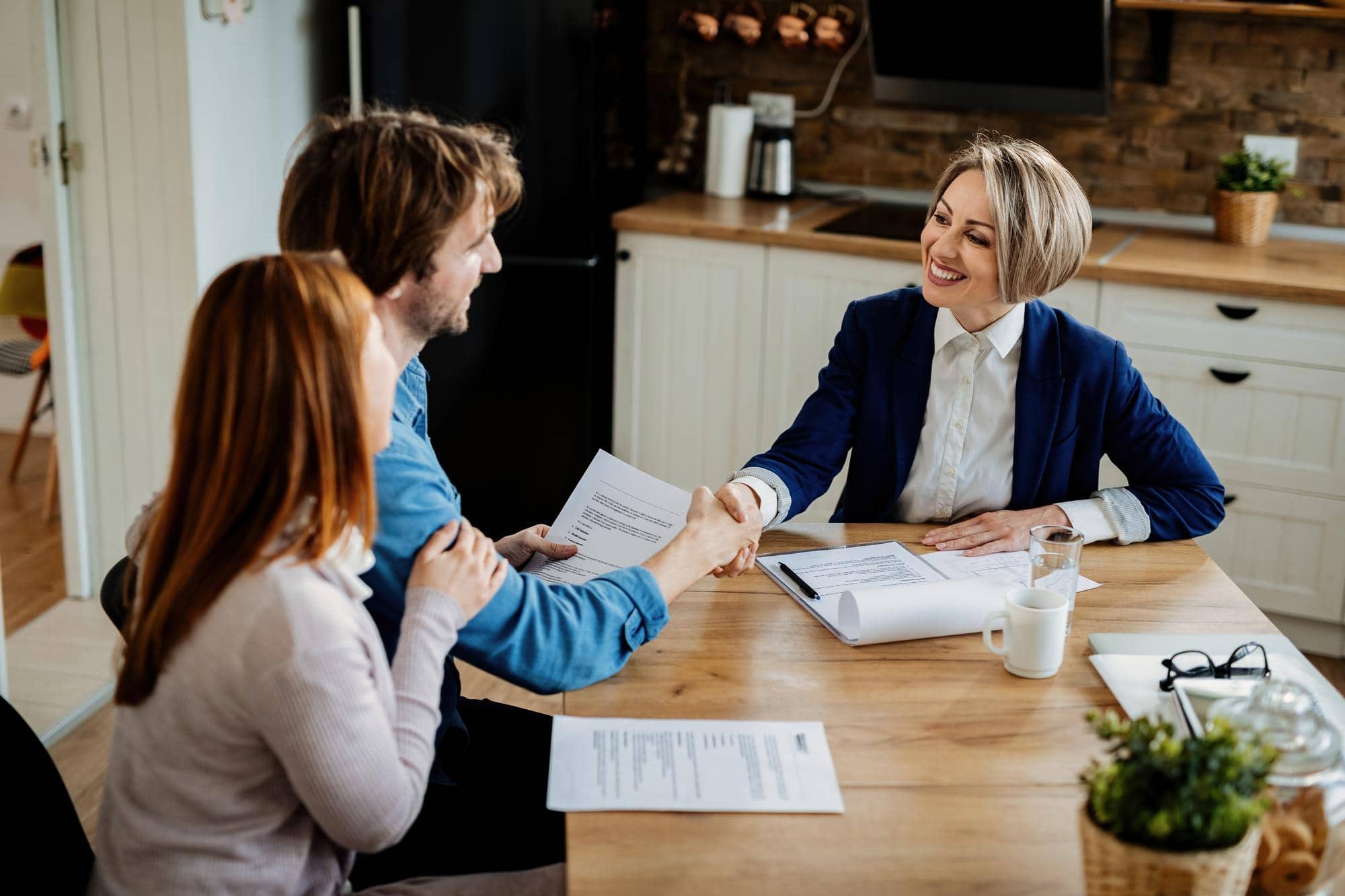 happy insurance agent shaking hands with young couple after successful meeting - Home Equity Loan - Using Your Home Equity Has Never Been Easier!