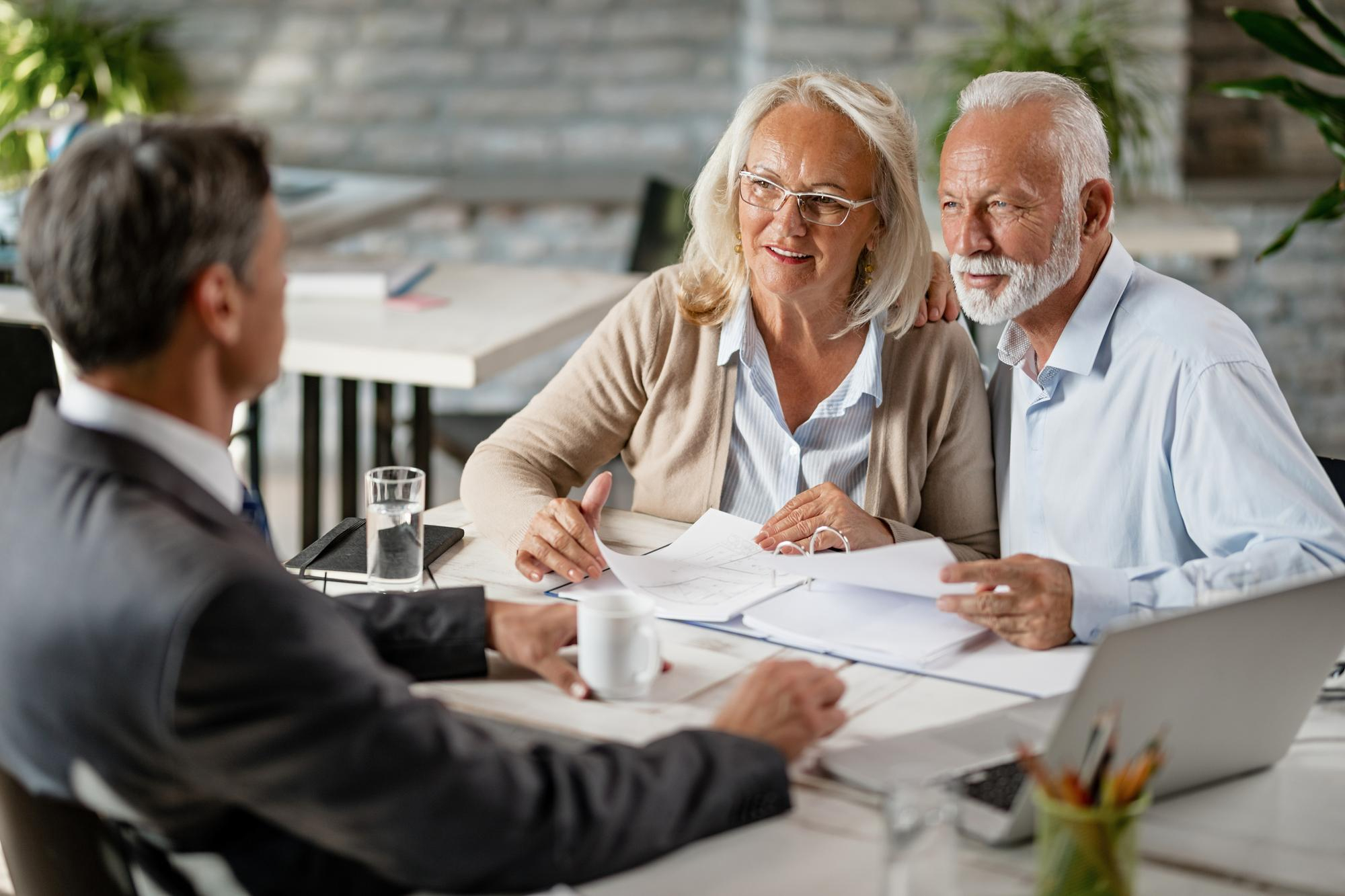 happy mature couple talking with real estate agent while analzying housing plans meeting office - Secured Line of Credit (HELOC)