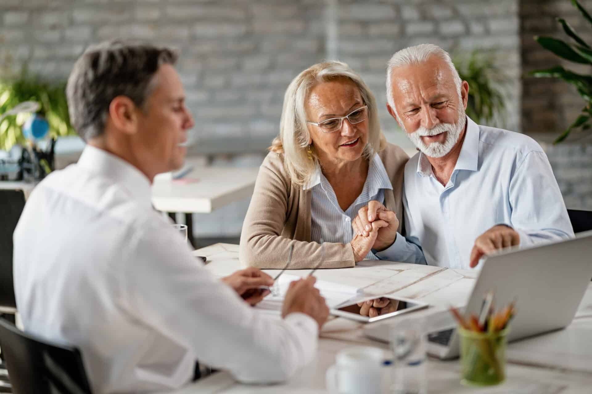 happy senior couple holding hands using laptop while having meeting with financial advisor office senior man is pointing something laptop - Alternative Mortgage Lenders - When the Big Banks Say "NO"