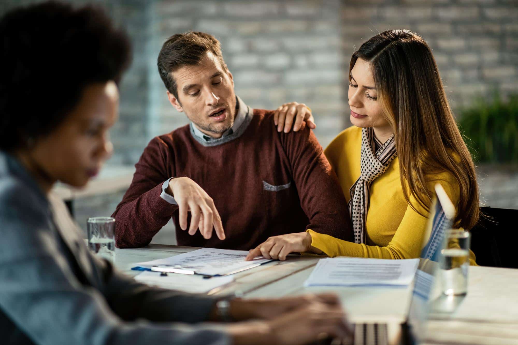 mid adult couple analyzing mortgage agreement while being meeting with real estate agent focus is woman pointing document - Mortgage Arrears - What if I Miss A Mortgage Payment?