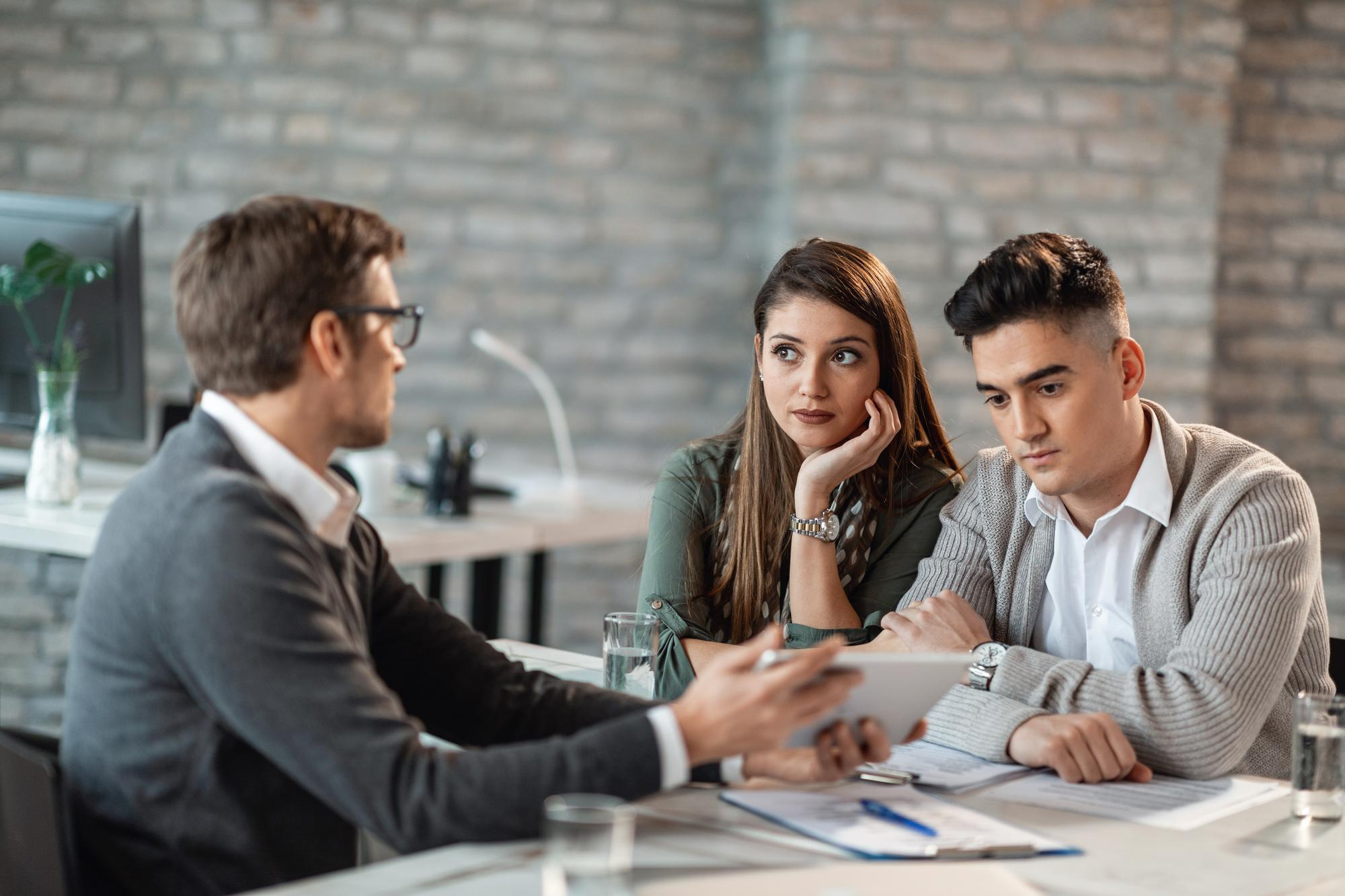 young couple financial consultant communicating while using digital tablet planning their future investments - Bad Credit Mortgages in Canada